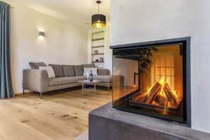 A modern living room with a sofa, a coffee table, and a fireplace. - Chalet with a terrace hot tub and sauna (Reit im Winkl)