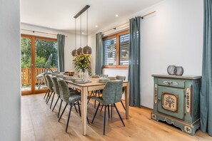A dining area with a wooden table, chairs, and a cabinet. - Chalet with a terrace hot tub and sauna (Reit im Winkl)