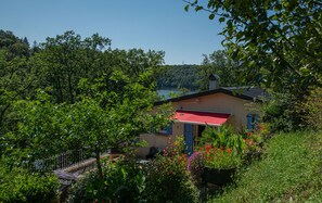 Ein Haus mit rotem Dach, umgeben von üppigem Grün und einem klaren Blick auf einen See.