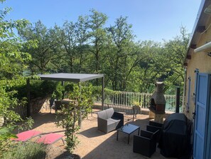 An outdoor patio with a covered seating area, a barbecue grill, and a pergola. - FISHERMAN'S COTTAGE—Secluded on the SHORES OF LAKE St. Etienne, CANTAL, AUVERGNE—A UNIQUE EXPERIENCE (Lacapelle-Viescamp)
