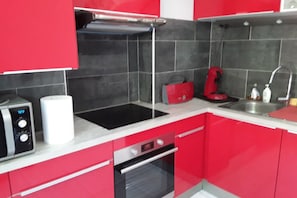 A kitchen with red cabinets, a microwave, a toaster, and a sink. - FISHERMAN'S COTTAGE—Secluded on the SHORES OF LAKE St. Etienne, CANTAL, AUVERGNE—A UNIQUE EXPERIENCE (Lacapelle-Viescamp)