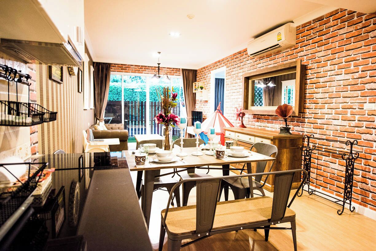 A dining area with a brick wall, a table set for four, and a view of the outdoors.