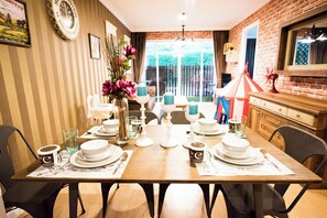 A dining area with a table set for four, chairs, a vase with flowers, and a brick wall. - A107 Cozy 2-bedroom apartment with Playground near Beach (Nongkae)