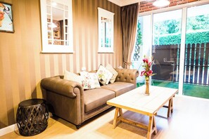 A cozy living room with a brown leather sofa, a wooden coffee table, and a small black side table. - A107 Cozy 2-bedroom apartment with Playground near Beach (Nongkae)