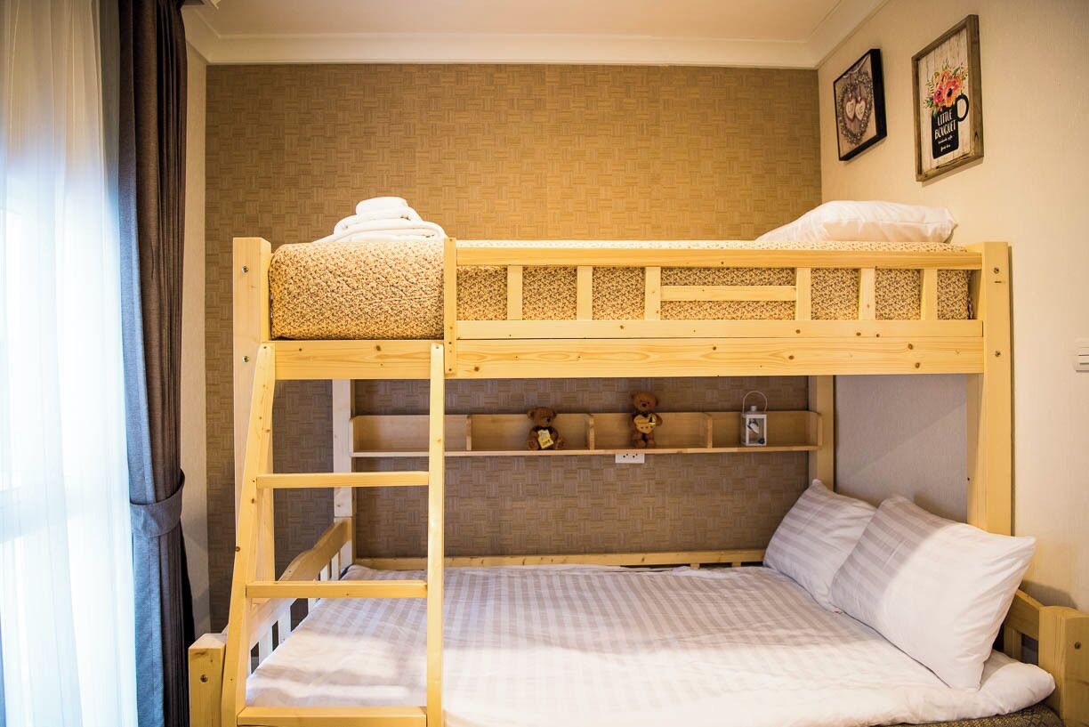 A bunk bed with a lower bunk, a shelf with teddy bears, and a wall with a patterned design.