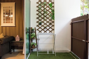 A room with a wooden lattice wall, a metal drying rack, a cushioned bench, and a small table with a lantern. - A107 Cozy 2-bedroom apartment with Playground near Beach (Nongkae)