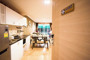 A modern kitchen with stainless steel appliances, a dining area with a wooden table, and a view of the outdoors. - A107 Cozy 2-bedroom apartment with Playground near Beach (Nongkae)
