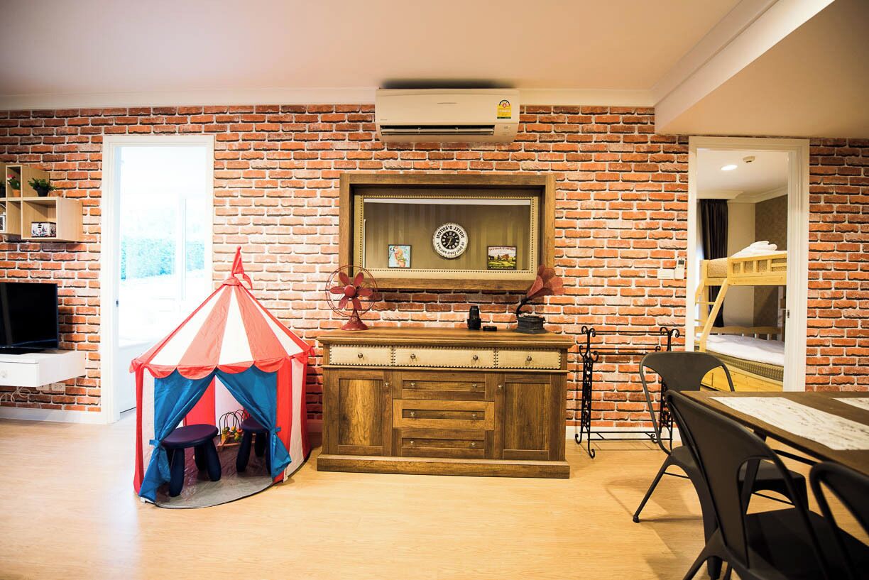 Ein Zimmer mit Backsteinwand, Holzschrank, Zelt und Etagenbett.
