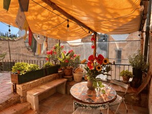 Une terrasse avec un sol carrelé, des plantes en pot, une table ronde et un banc.