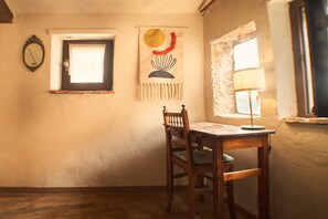 Une pièce comprenant une table en bois, une chaise, une tapisserie murale, une fenêtre avec une lampe et un miroir.