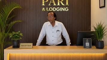 A reception desk with a sign reading 'HOTEL PARI & LODGING.'