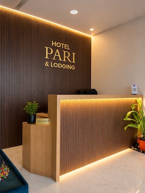 Un mostrador de recepción con acabado de madera y un letrero que dice 'HOTEL PARI & LODGING'.