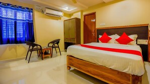 Una habitación de hotel con cama, escritorio, silla, aire acondicionado y armario.
