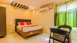 Habitación de hotel con cama, una silla, equipo de aire acondicionado y ventana con cortinas.