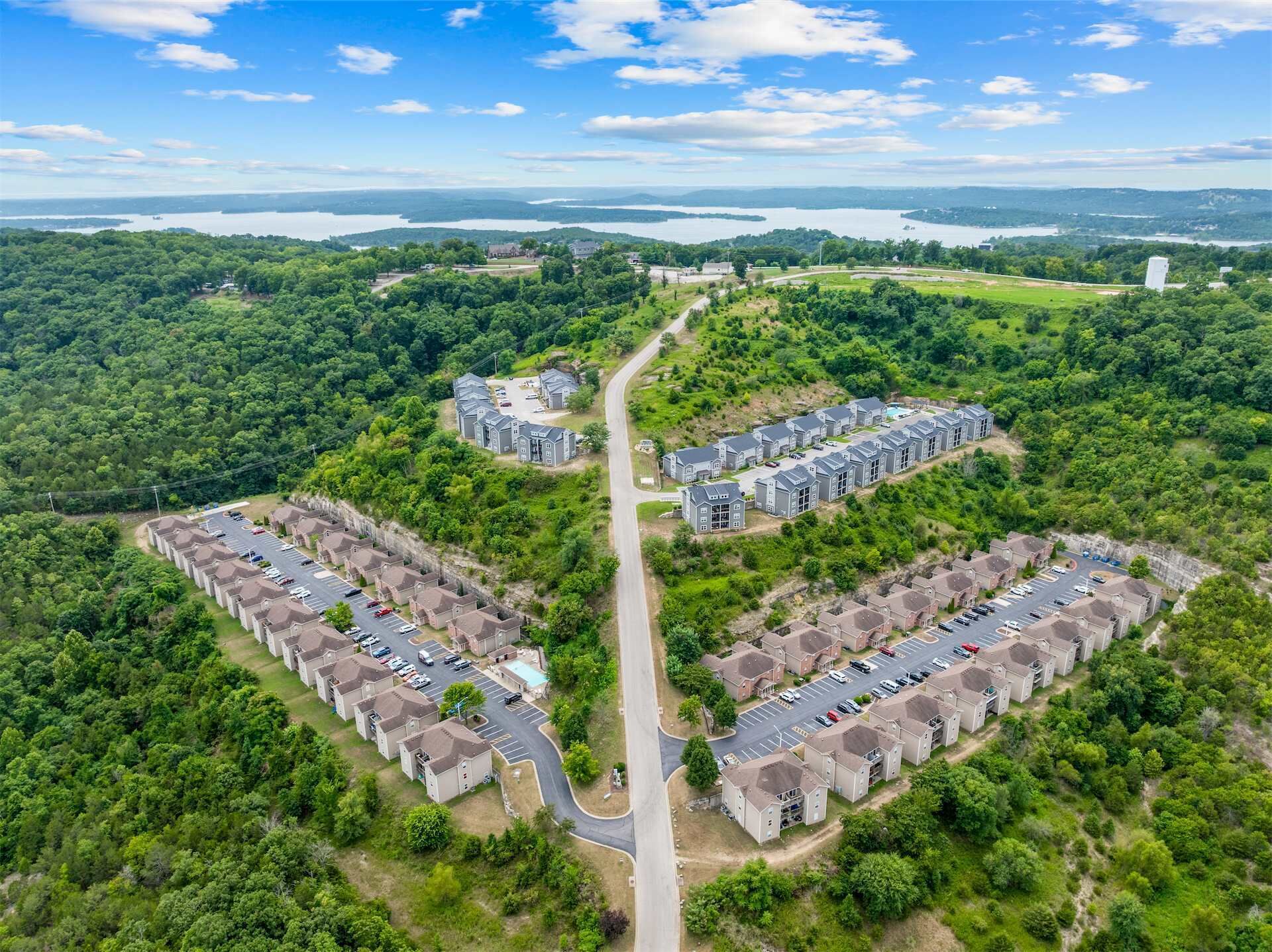 A residential area with two clusters of townhouses, a central road, and surrounding greenery.
