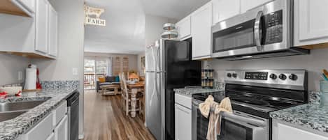 A modern kitchen with stainless steel appliances, a wooden dining table, and a sign that reads 'FARM'.