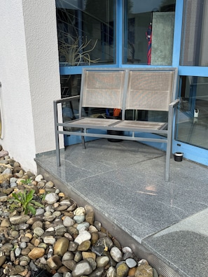 A bench outside a building with a stone pathway and a glass door. - Ideal for golfers, cyclists, and recreational athletes—3-room apartment in a central location (Krauchenwies)