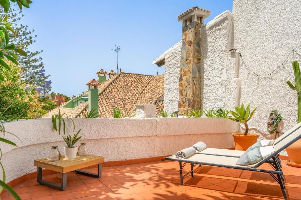 A terrace with a lounge chair, a small table, and potted plants.