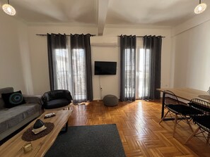 Ein Wohnzimmer mit einer Couch, einem Couchtisch, einem Fernseher und einem Essbereich mit Stühlen.