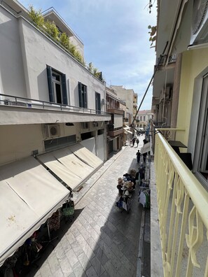 A narrow street with buildings on either side, some with balconies and air conditioning units.
