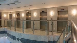 A modern elevator area with glass railings and marble flooring.