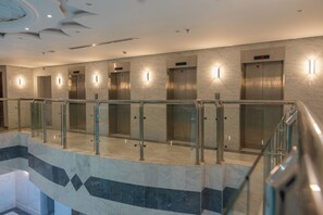 A modern elevator area with glass railings and marble flooring.