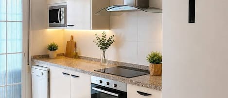 Eine moderne Küche mit weißen Schränken, einem eingebauten Backofen, einer Mikrowelle und einer Edelstahl-Dunstabzugshaube.