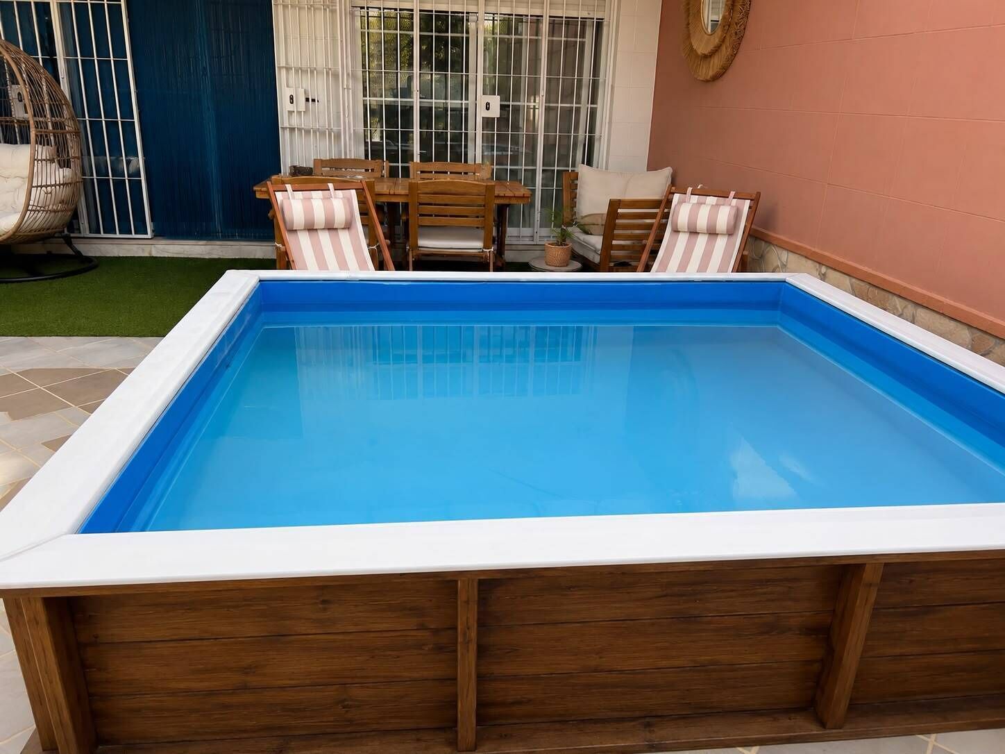 A rectangular swimming pool with a wooden deck surrounding it.