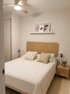A neatly made bed with a patterned bedspread, a wooden headboard, and two bedside tables with lamps and a small plant. - Baviera Golf | Private Pool, Terrace & Costa del Sol (Vélez-Málaga)