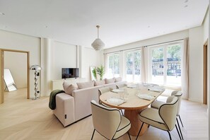 A modern living room with a sofa, a dining table set for six, and a television. - Modern a/c - 2bdr/4p Flat - Montorgueil (Paris)