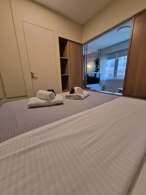 A hotel room with a large bed, a wardrobe, and a sliding glass door leading to a balcony. - Apollonos 26 Luxury Suite (Athina)