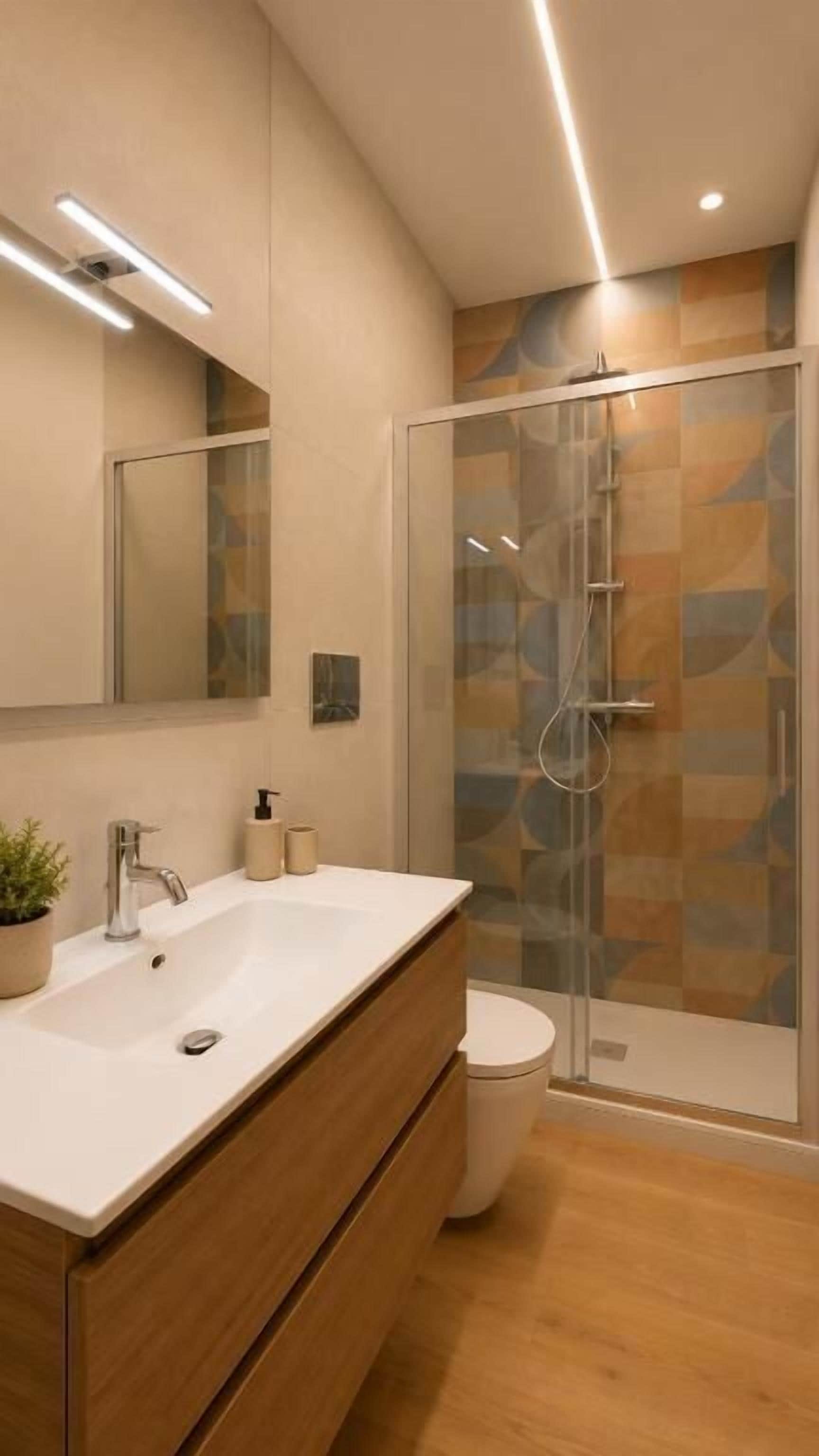 Une salle de bain moderne avec une douche à parois de verre, un lavabo blanc et des toilettes.