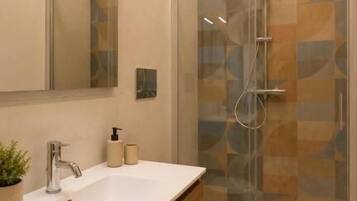 Une salle de bain moderne avec une douche à parois de verre, un lavabo blanc et des toilettes.