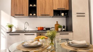 Una cocina moderna con armarios de madera, una mesa redonda de vidrio preparada para comer, y una variedad de utensilios de cocina.
