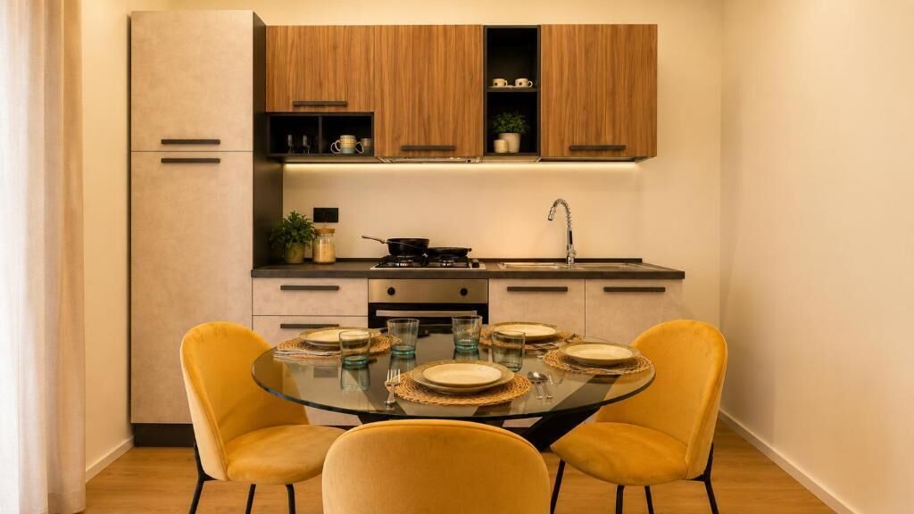 A compact kitchen with a dining table set for four, equipped with a stove, sink, and cabinets.