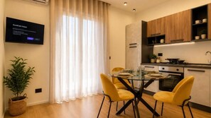 A modern kitchen with a dining table, chairs, and a television mounted on the wall.