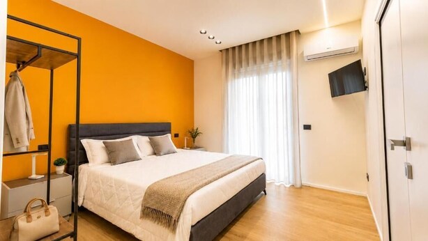 Un dormitorio con cama, armario, televisión y ventana con cortinas.