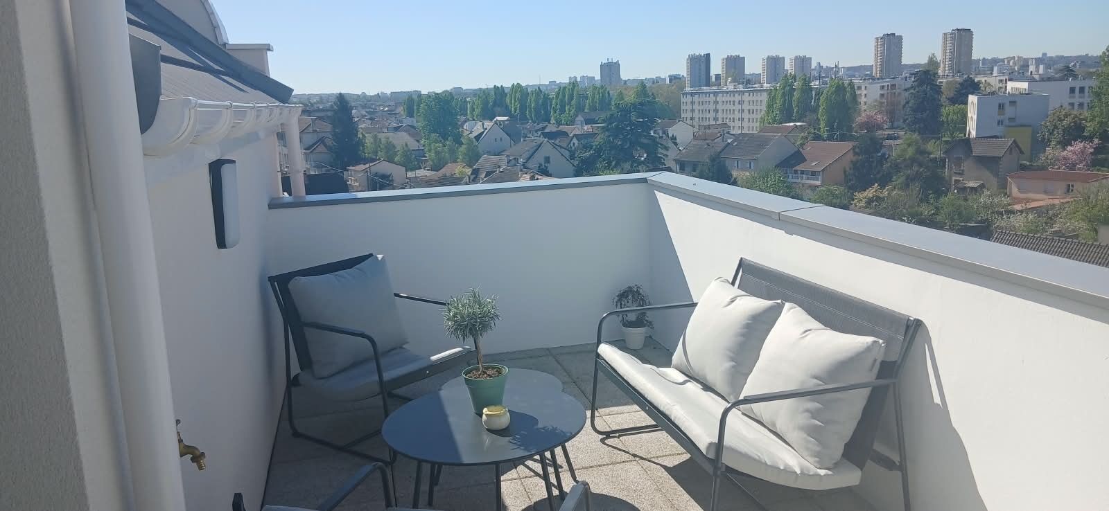 Un balcon avec un canapé, une petite table et une plante en pot.