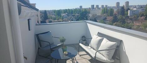 Un balcon avec un canapé, une petite table et une plante en pot.