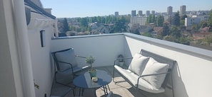 Ein Balkon mit einer Couch, einem kleinen Tisch und einem Blumentopf.