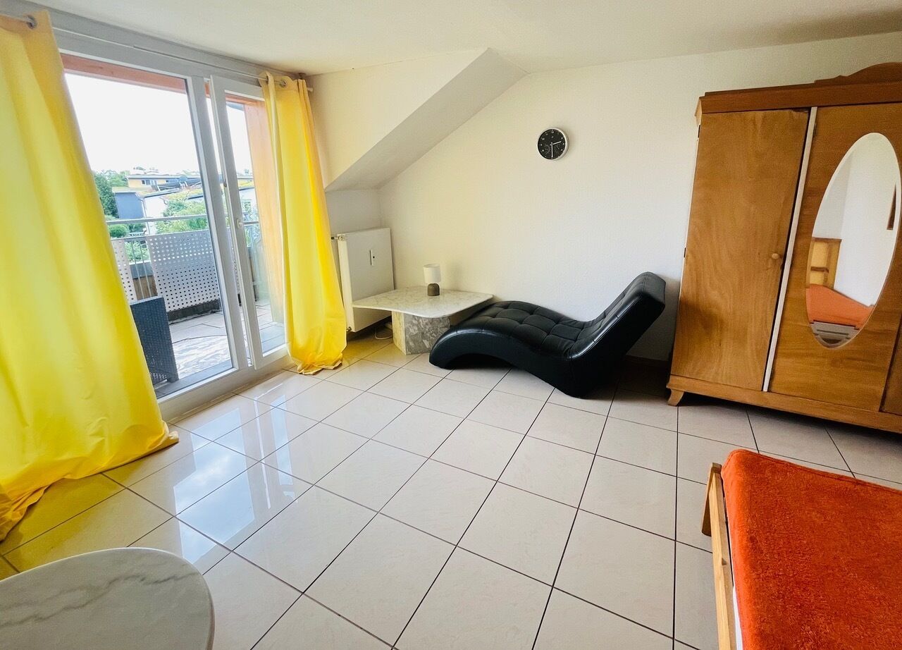 Una habitación con piso de baldosas, un armario de madera, una silla de masaje negra y una ventana con cortinas amarillas.