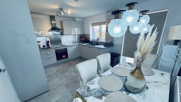 A modern kitchen with a dining area, featuring a marble countertop, a chandelier, and a view of the outdoors. - Room-stylish Modern Double Room With pri (Peterborough)