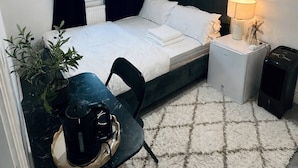 A neatly arranged bedroom with a bed, bedside table, lamp, and a small heater. - Room-stylish Modern Double Room With pri (Peterborough)