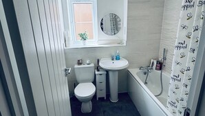 A modern bathroom with a toilet, sink, and bathtub. - Room-stylish Modern Double Room With pri (Peterborough)