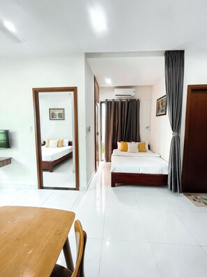 A hotel room with a bed, a TV, a dining table, and a mirror. - Green Apartment near My Khe Beach and Dragon Bridge- 201 (Đà Nẵng)