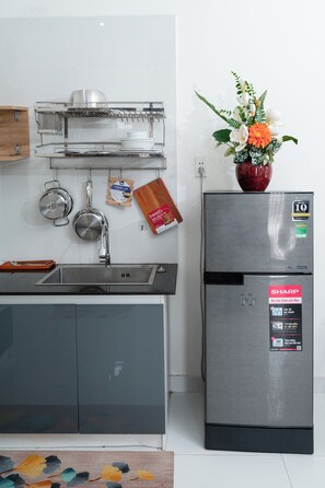 A kitchen with a stainless steel refrigerator, a sink, and a hanging pot rack. - Green Apartment near My Khe Beach and Dragon Bridge- 201 (Đà Nẵng)