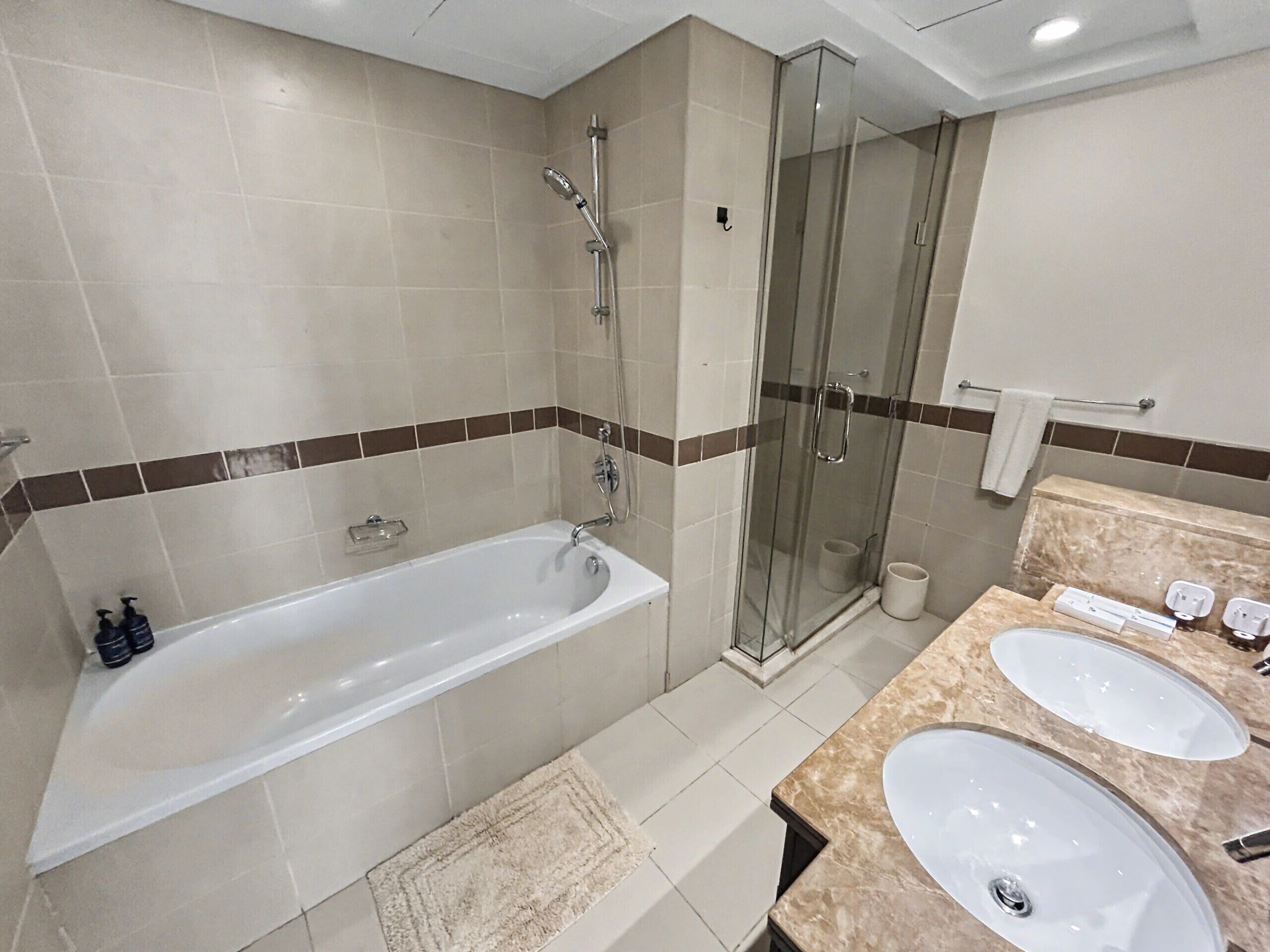 Un baño moderno con bañera, ducha con mampara de vidrio y tocador doble.