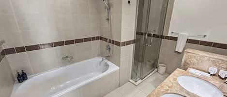 A modern bathroom with a bathtub, a glass-enclosed shower, and a vanity with two sinks.