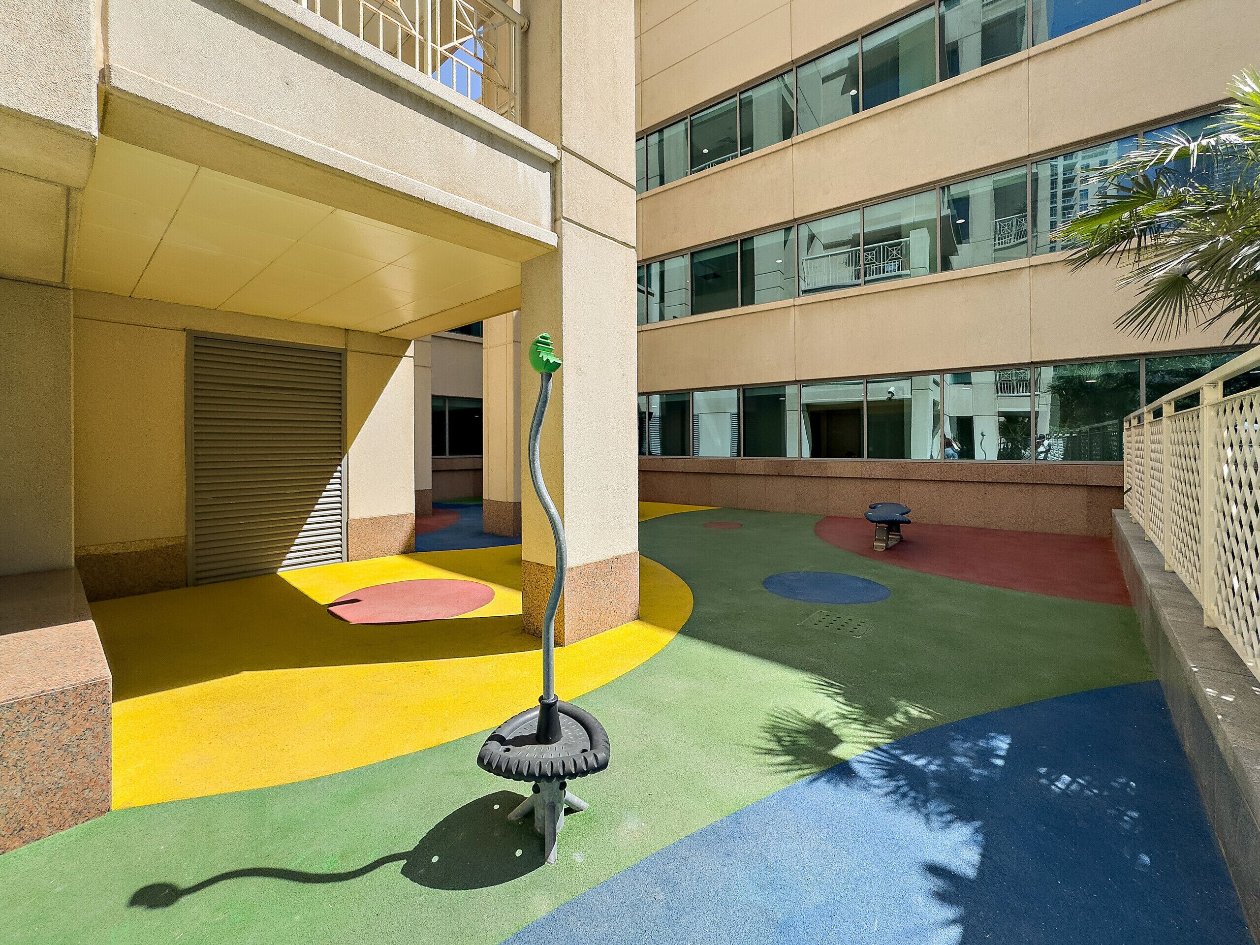 Ein mehrgeschossiges Gebäude mit einem Kinderspielbereich, der farbenfrohe Bodenbeläge und eine Schaukel besitzt.