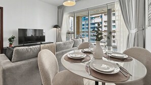 Moderni olohuone, jossa on sohva, neljän hengen ruokapöytä ja televisio.